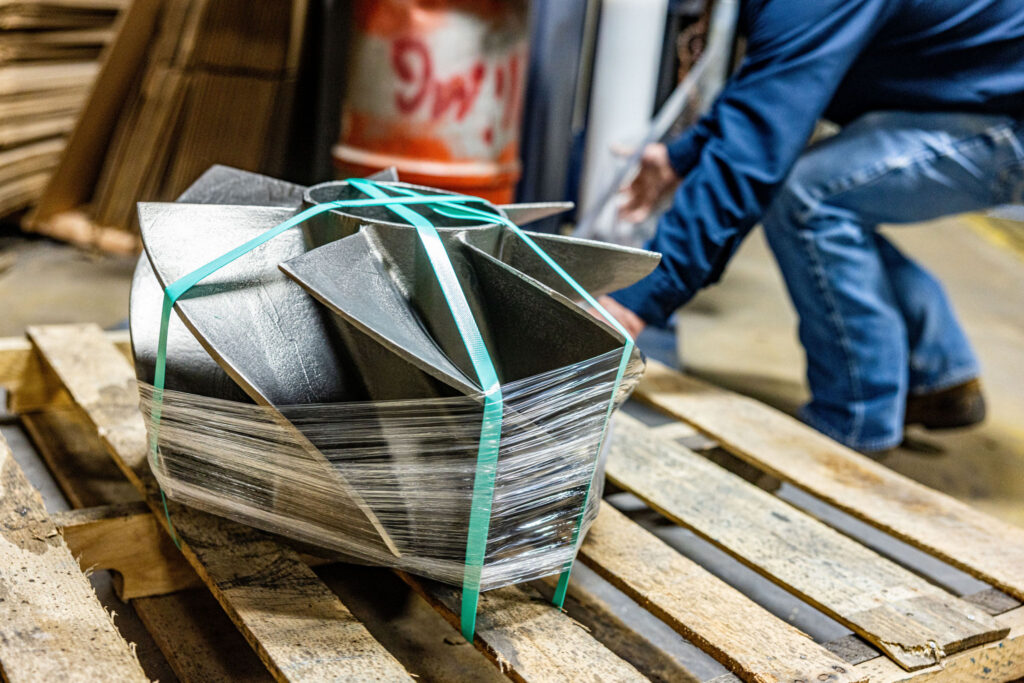A man wrapping a product in plastic getting it ready for shipment.