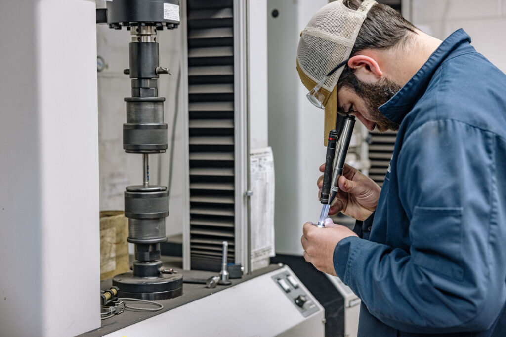 A man inspecting a part in the quality control lab.