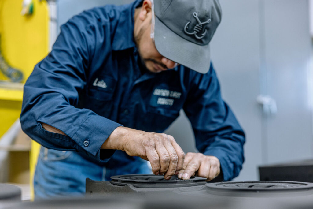A man inspecting a newly casted 3D sand print.